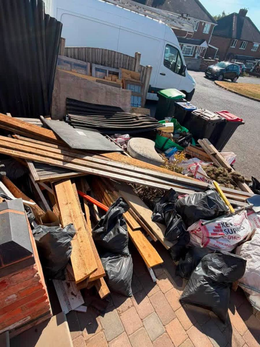 Driveway covered in builders' waste, timber and rubble bags before clearance