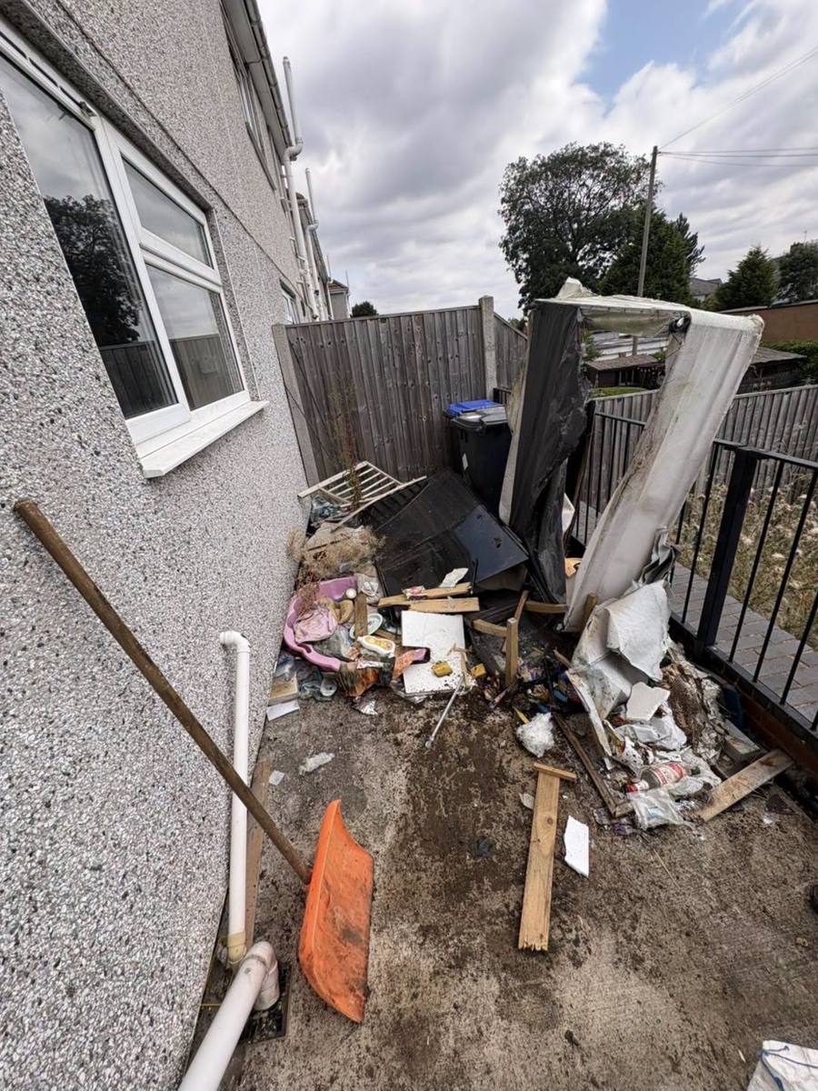 Side passage filled with broken furniture and general waste before clearance