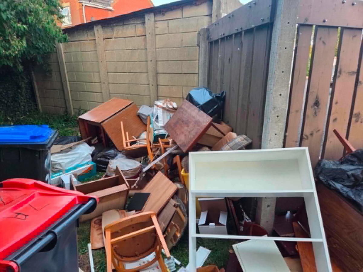 Old furniture piled up for collection, including a dresser, chairs and a sofa